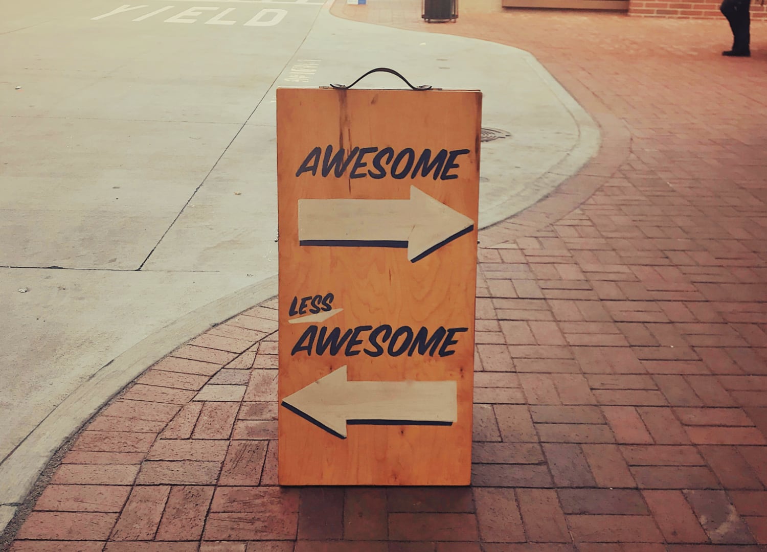 Sandwich board that points to the right with the phrase "awesome" and points to the left with the phrase "less awesome."